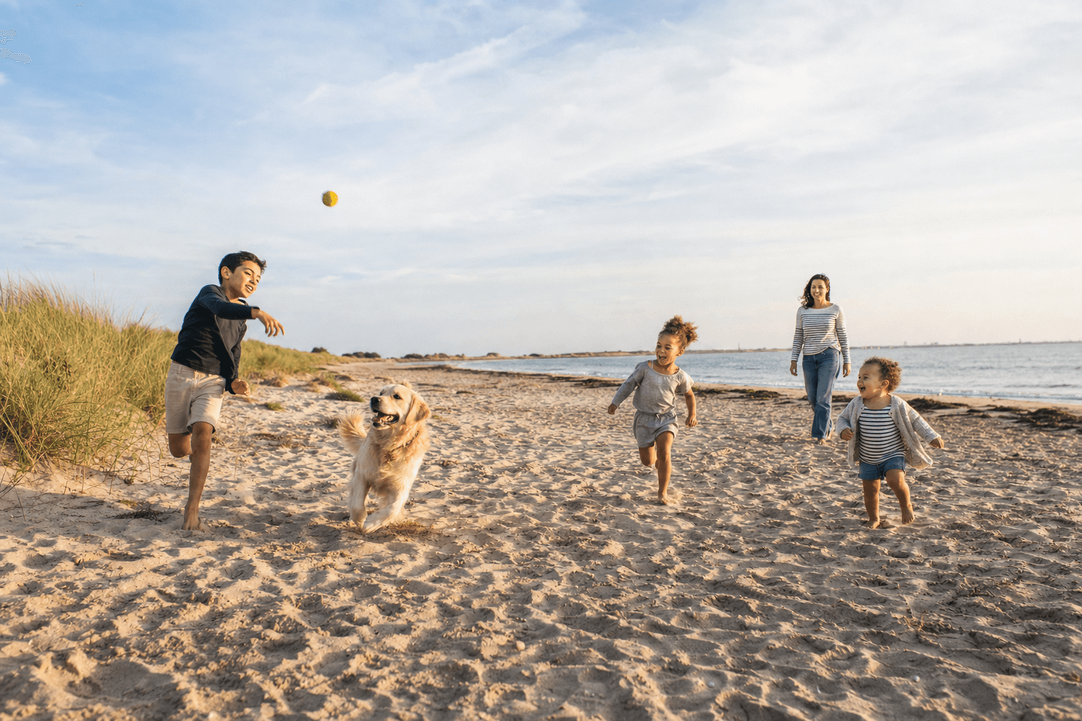 Des enfants jouant à la balle avec un chien sur la plage
