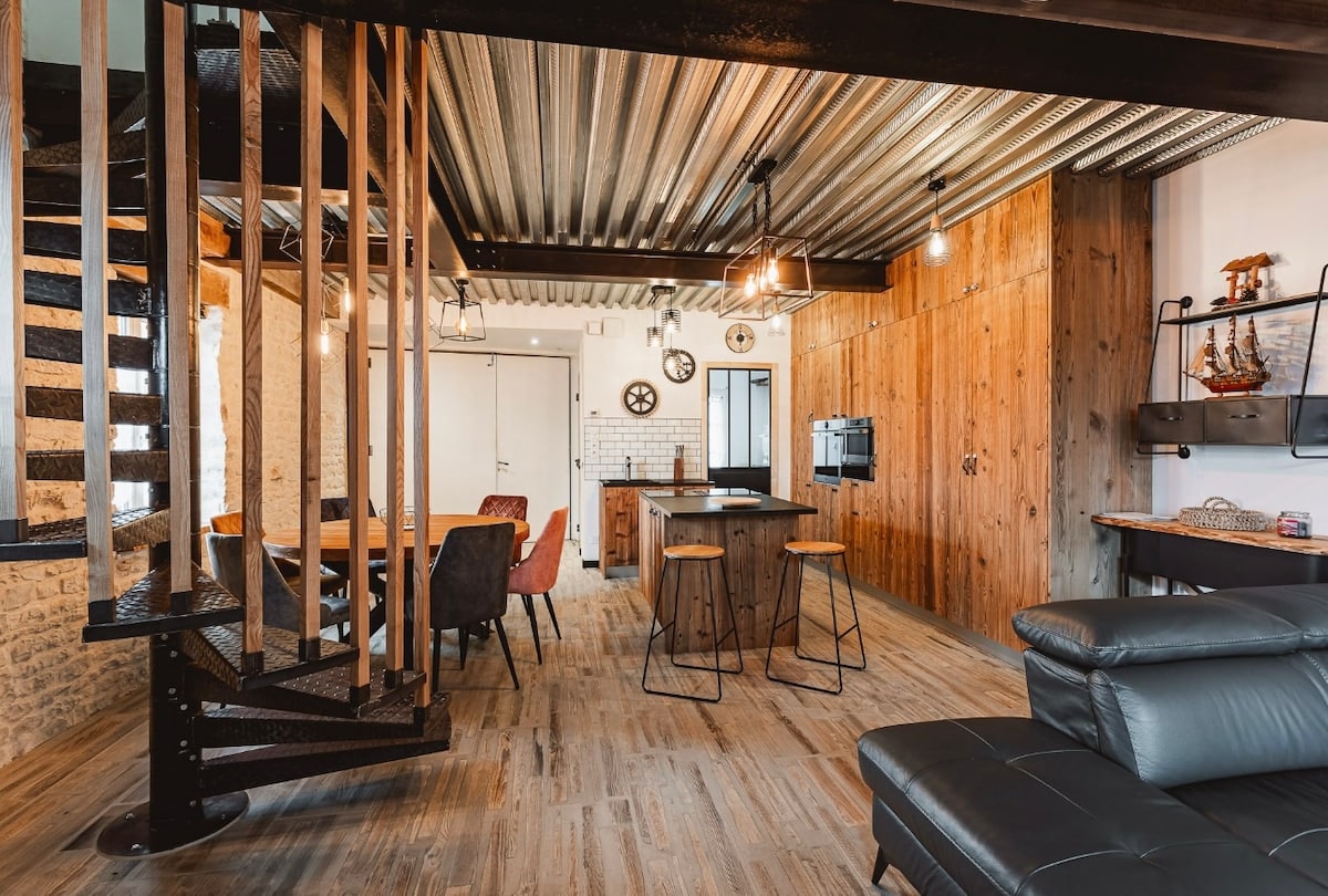 Le salon du Chai avec ses murs en pierre et sa charpente apparente