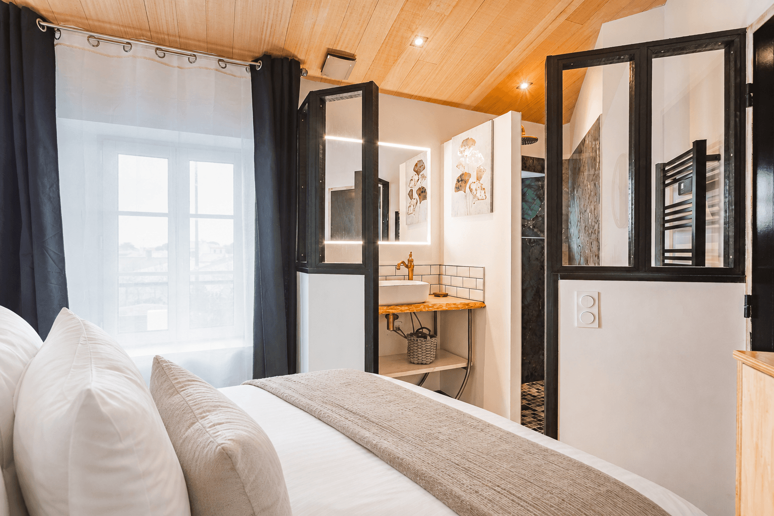 Une chambre du Chai préparée avec soin et ouverte sur sa salle d’eau