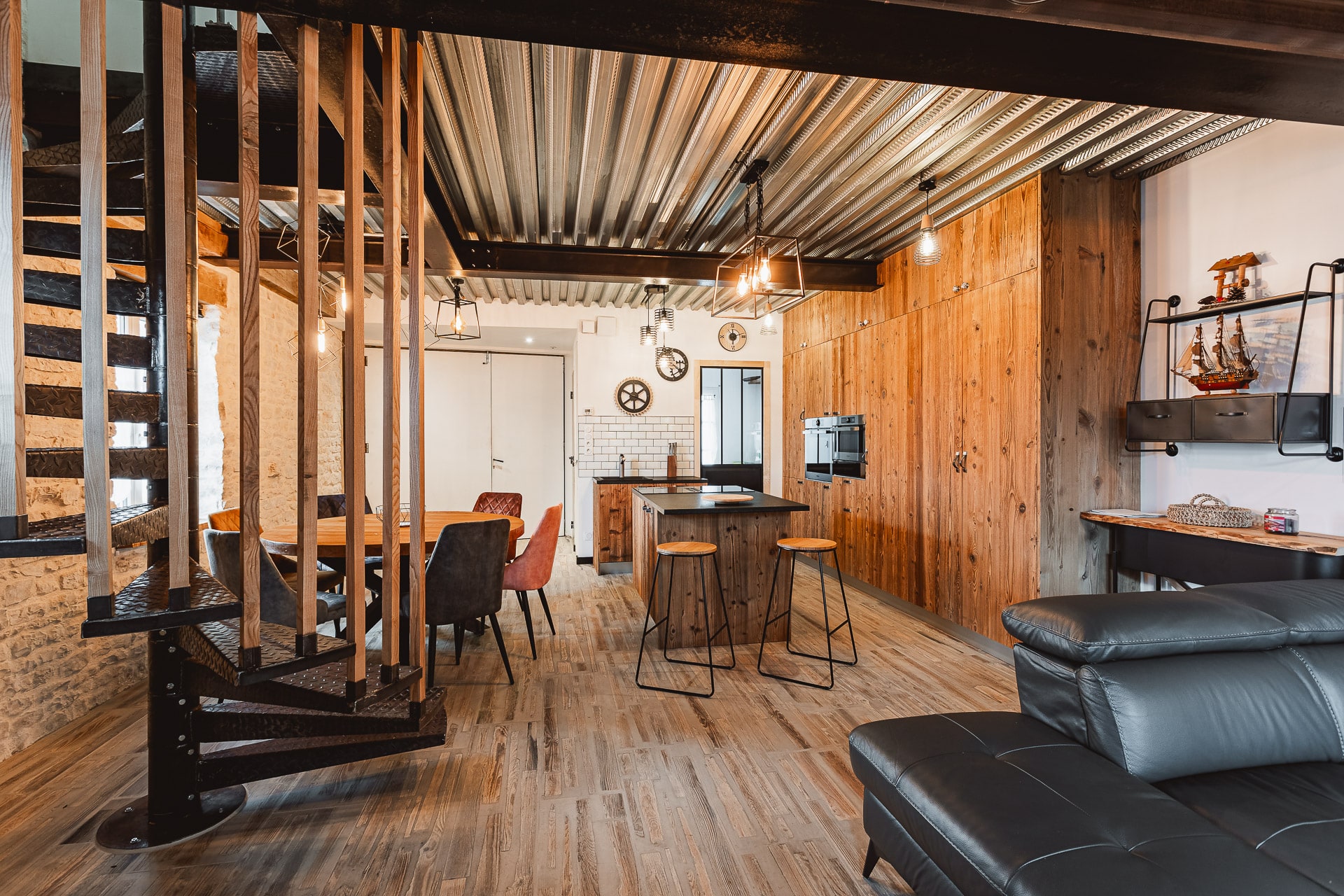 Le séjour du Chai avec la cuisine en bois et l’escalier en colimaçon