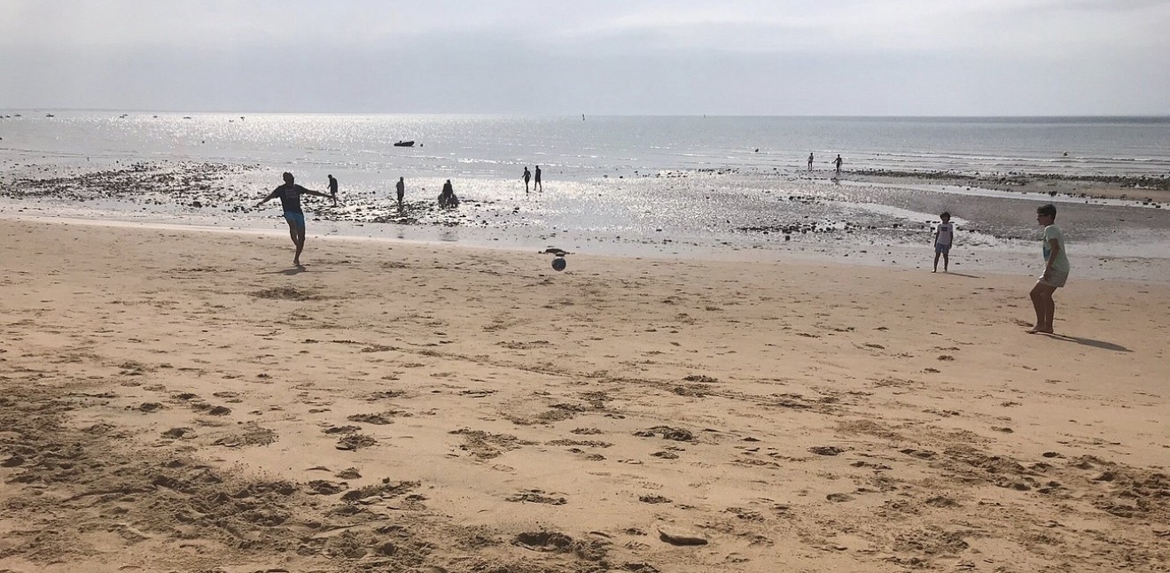 Familles en tenue d’été jouant sur la plage à marée basse