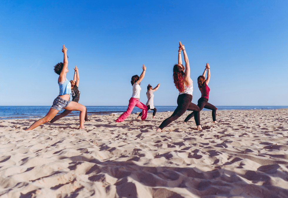 Séance collective de yoga sur une plage face à l’océan