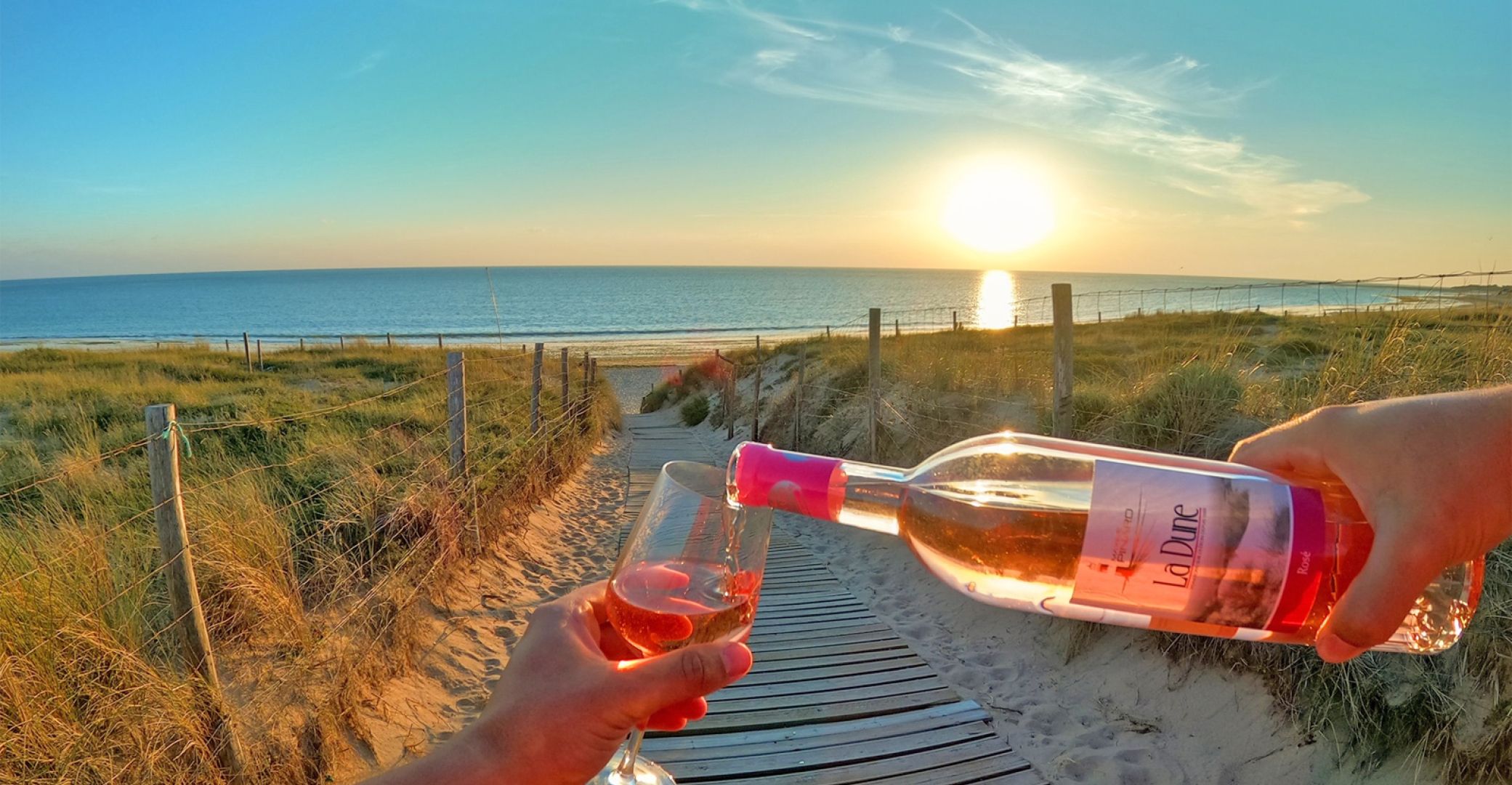Verres de vin rosé face à l’océan au coucher du soleil