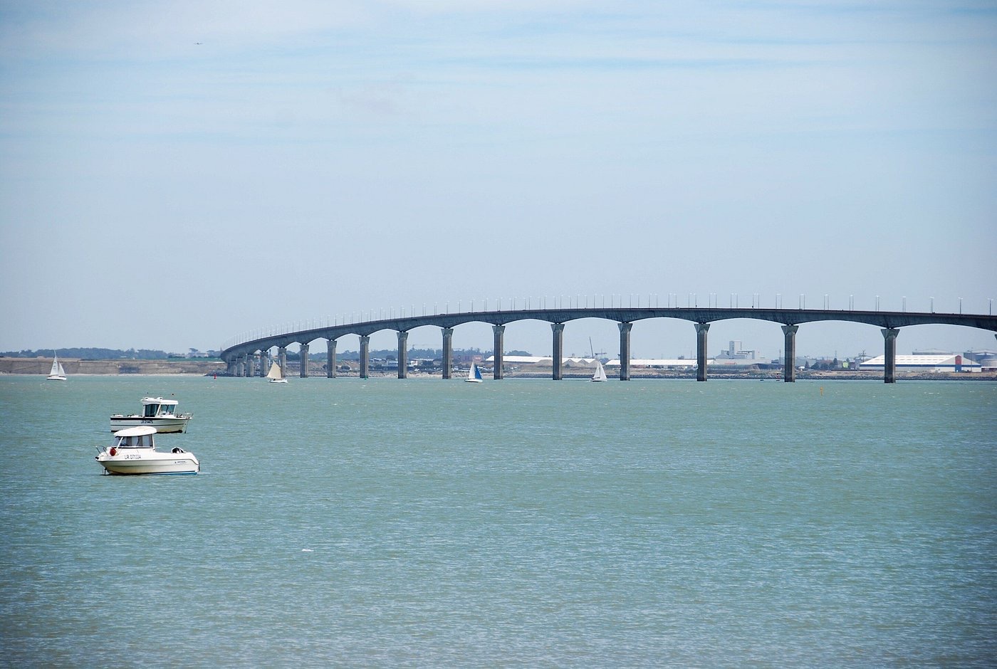 Pont de l’Île de Ré vu depuis le littoral avec des voiliers et des bateaux au premier plan