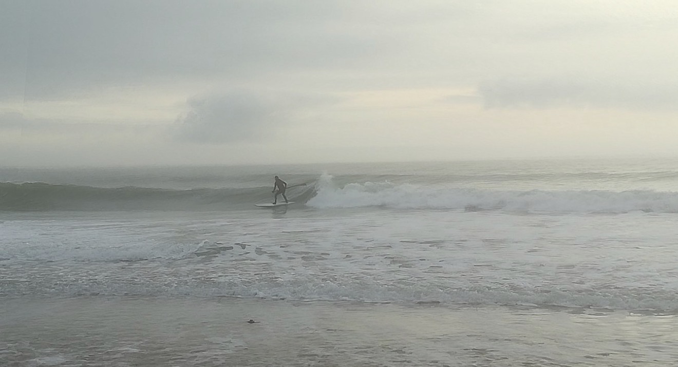 Surfeur solitaire dans la brume et les vagues de l’océan en hiver
