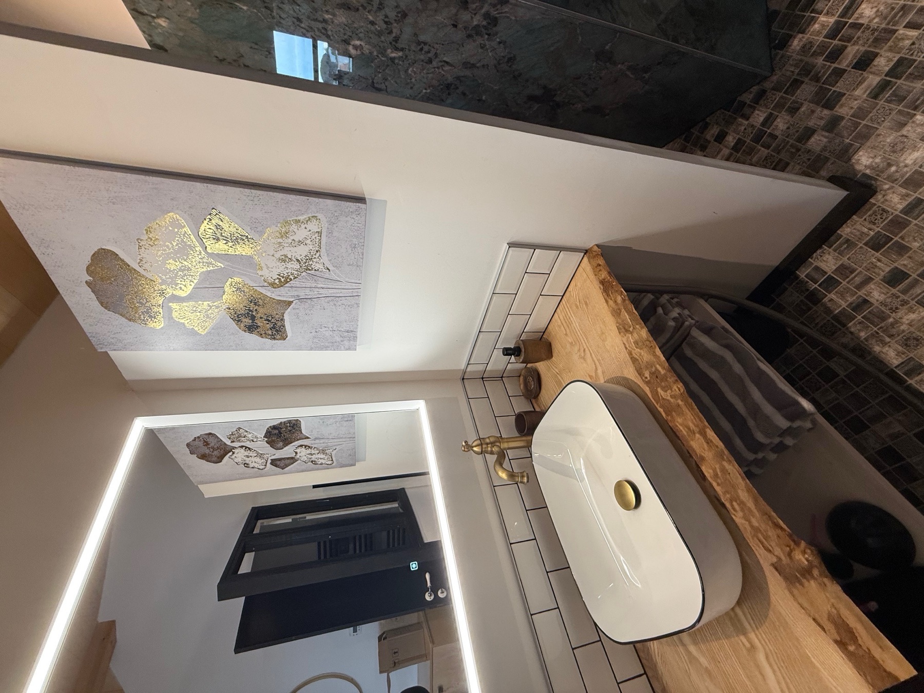 Salle d’eau du Chai avec vasque en bois, miroir éclairé et douche minérale
