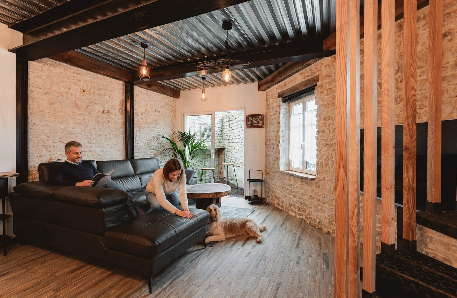 Un couple séjournant avec son chien dans le salon du Chai