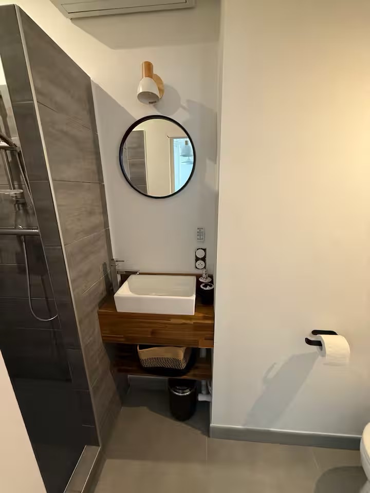 Salle d’eau de Villa Raie Manta avec douche, vasque en bois et miroir rond